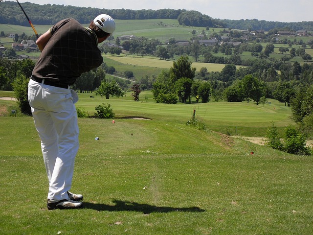 a golfer teeing off on a par four on a hilly course