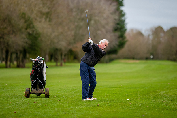 an older golfer with an electric trolley